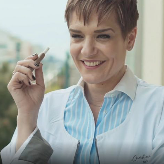woman smiling while holding an IQOS