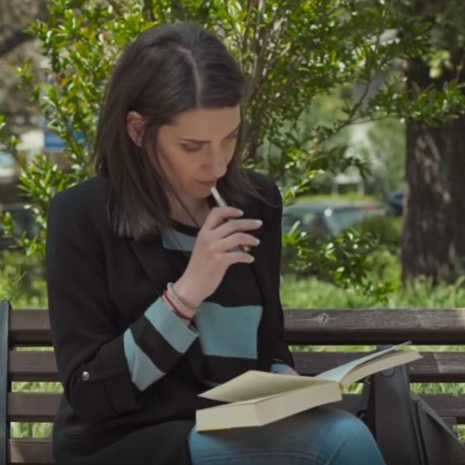 A woman in street holding an IQOS device