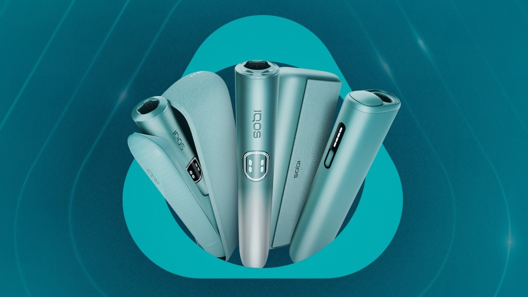 Μία πράσινη βάση IQOS ILUMA σε πορτοκαλί φόντο