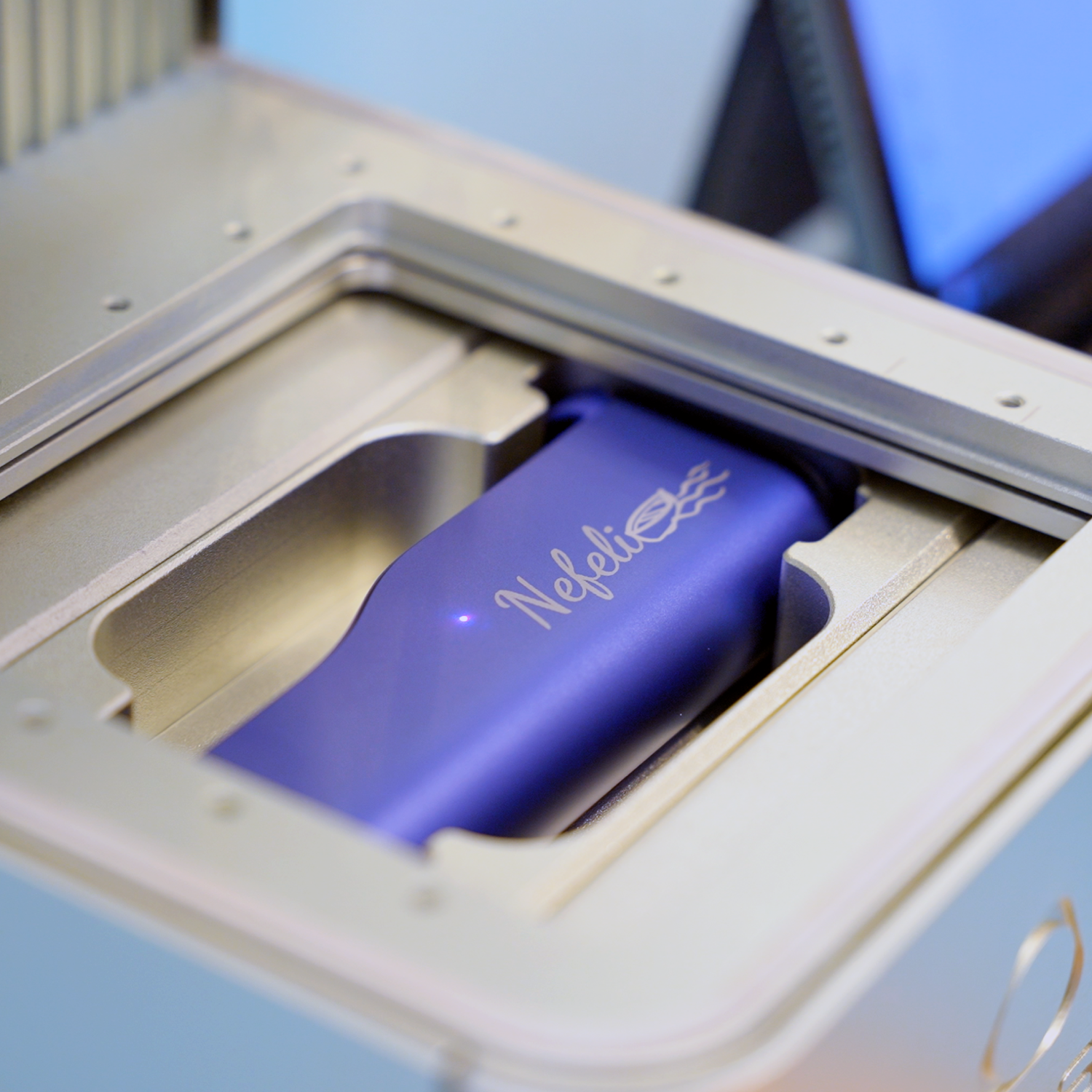 Ένα IQOS ILUMA i PRIME σε χρώμα Electric Purple με εξατομικευμένη χάραξη, μέσα σε μια μηχανή χάραξης σε ένα κατάστημα IQOS.