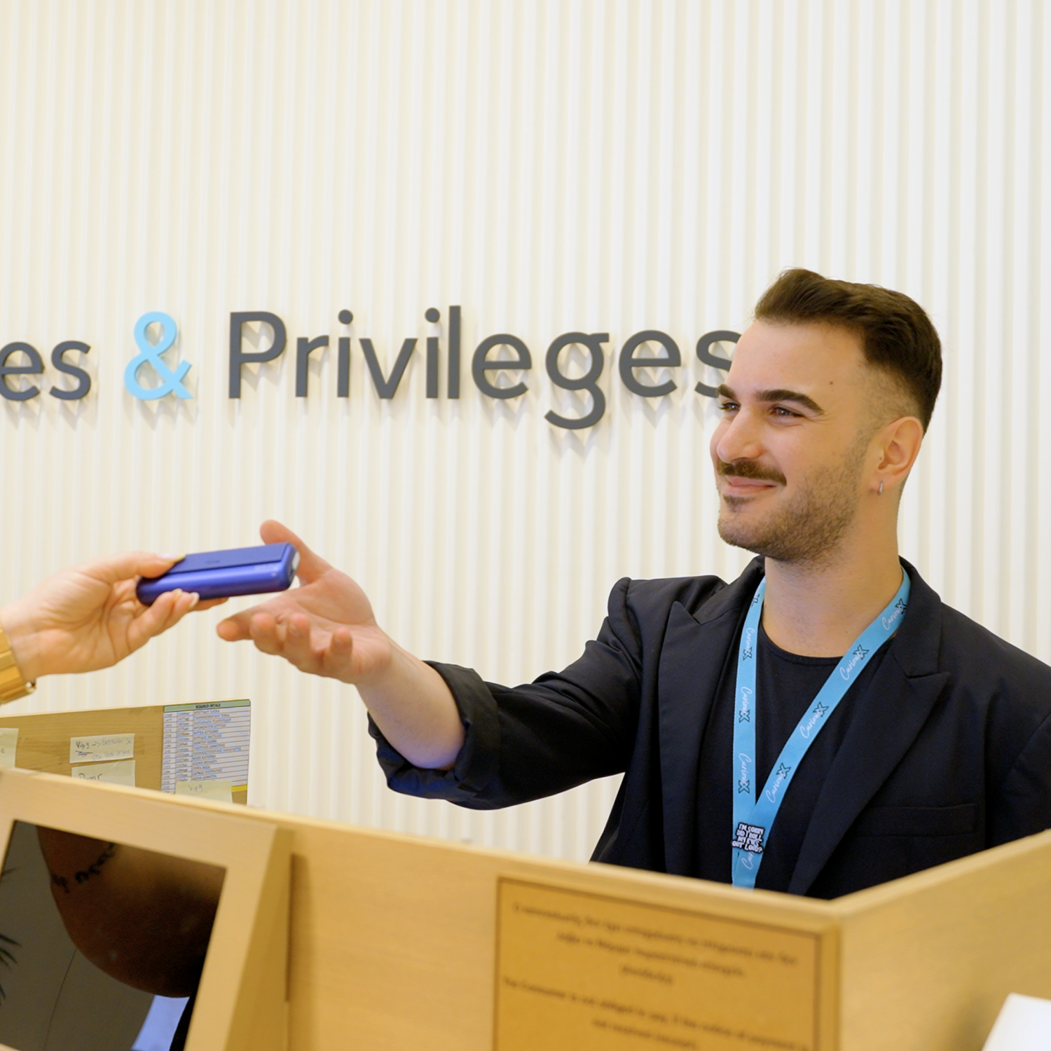 Μέλος της ομάδας του IQOS Store που βοηθά έναν πελάτη με μια συσκευή IQOS στο γραφείο εξυπηρέτησης πελατών.