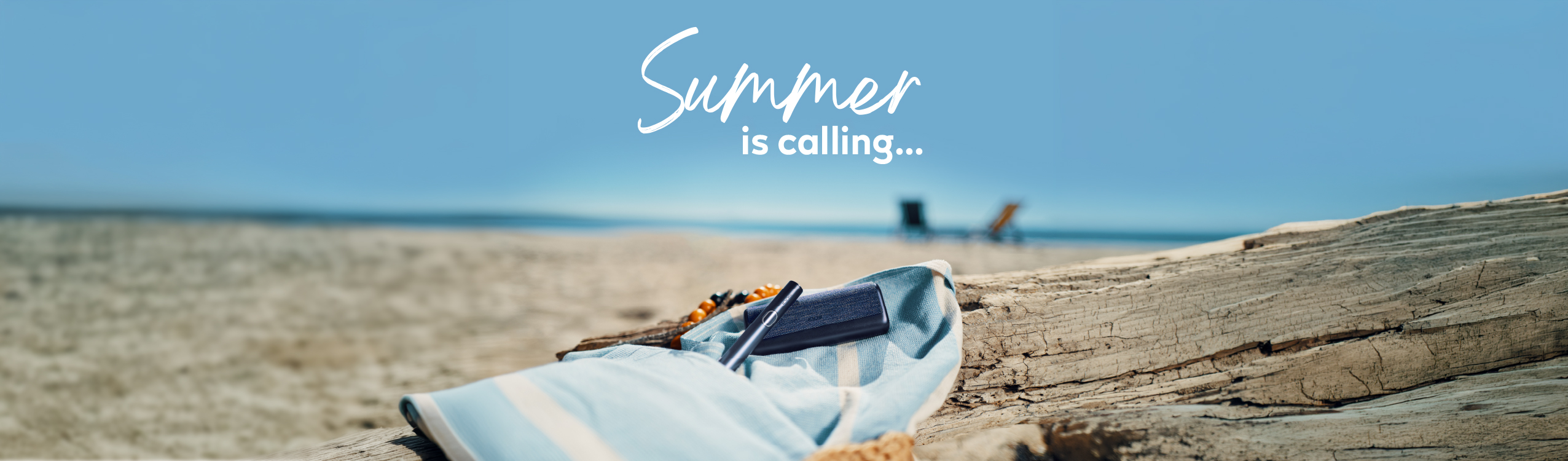 IQOS device on a beach towel at the beach with the text Summer is calling...