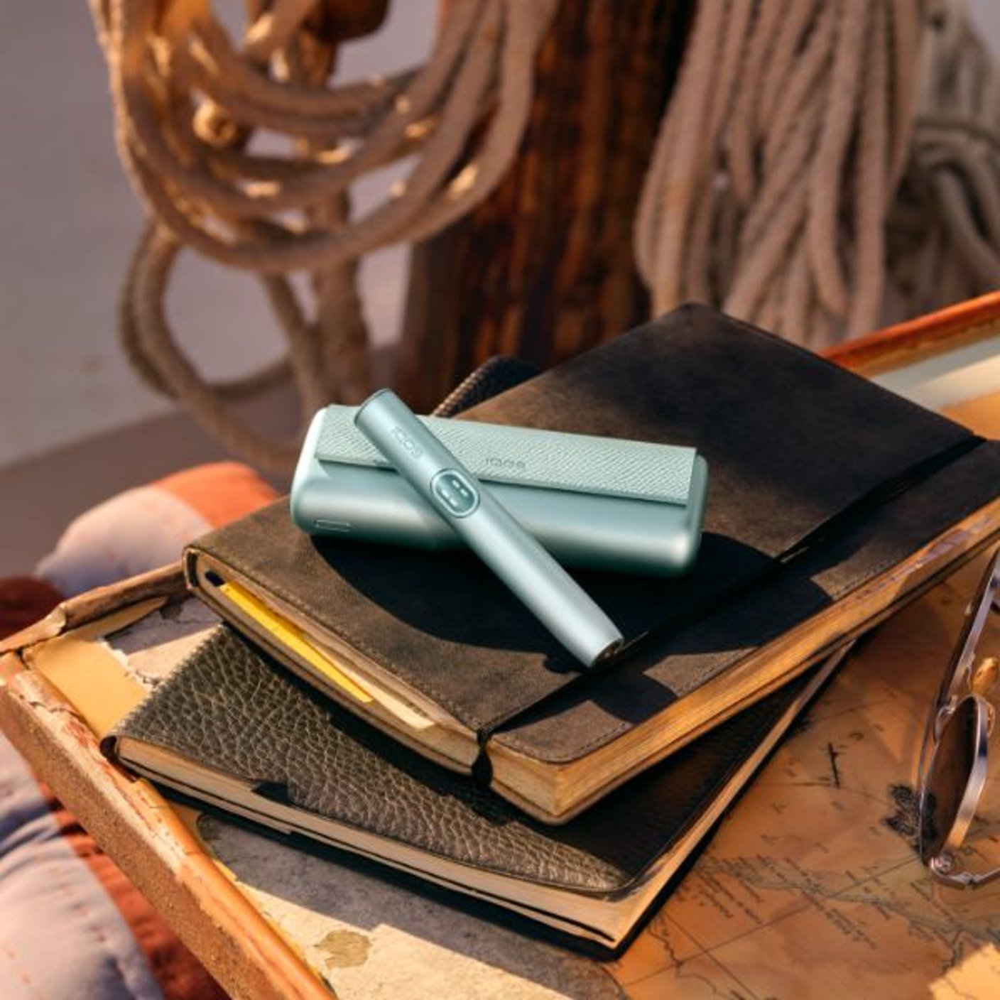 An IQOS ILUMA i PRIME device placed on top of old books.