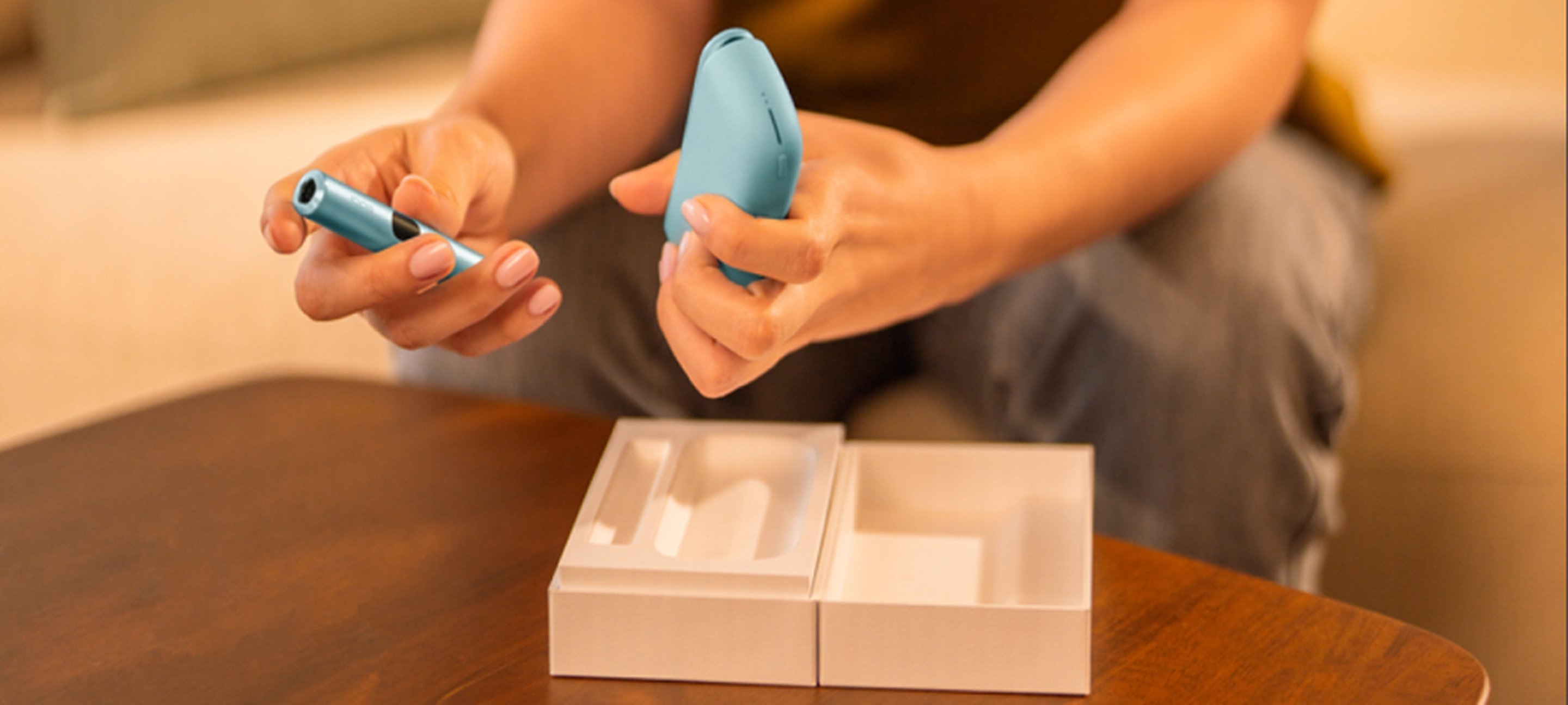 A hand is holding an IQOS ILUMA i ONE.