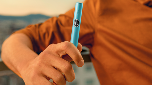 Male hand holding a Breeze Blue IQOS ILUMA i device.