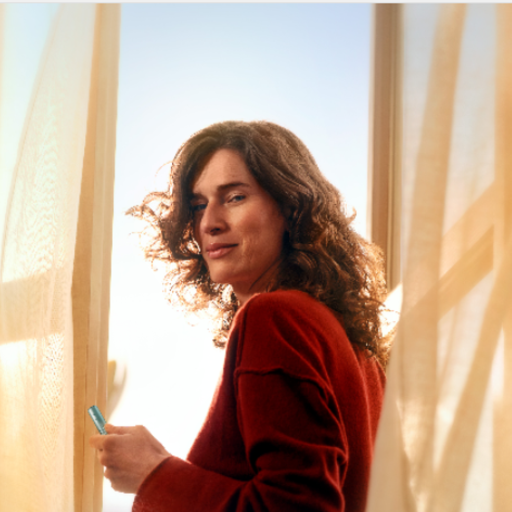 A Moss Green IQOS ILUMA holder in orange background.