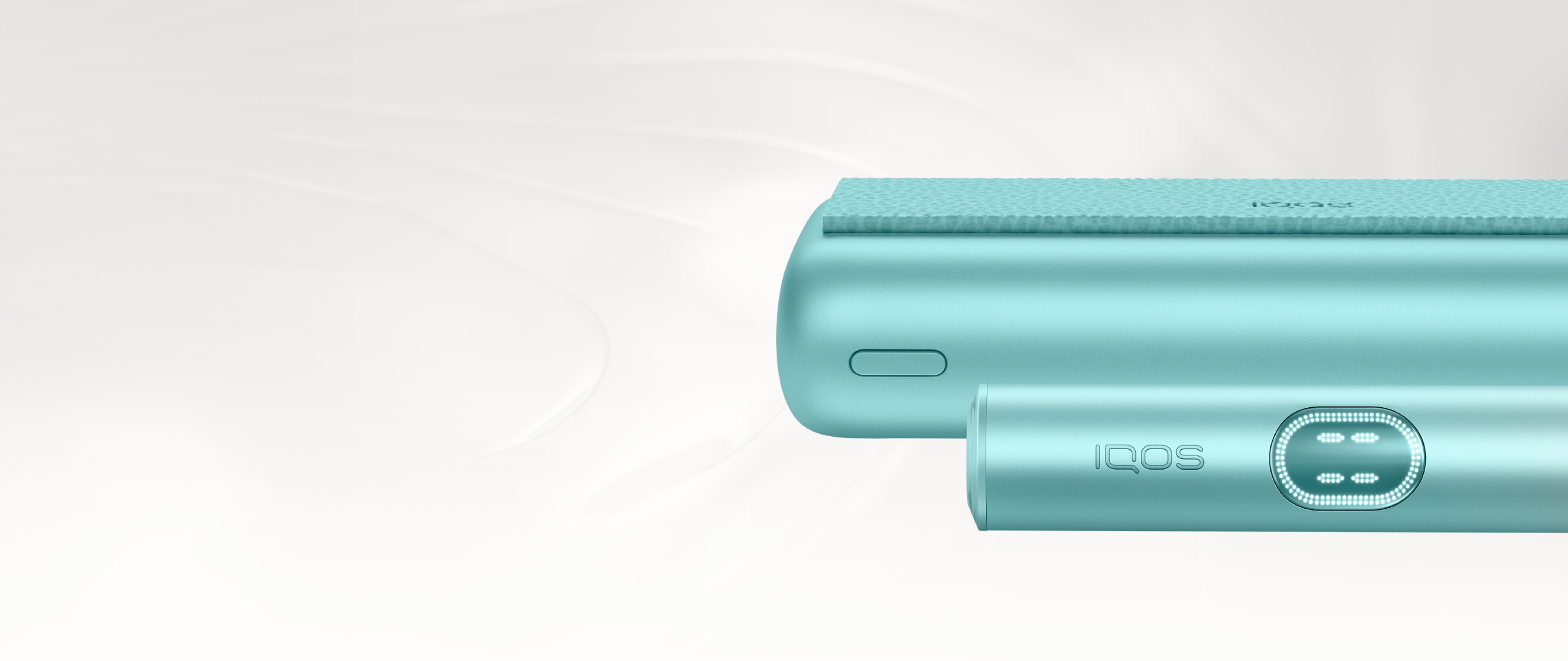 Close up of a Breeze Blue IQOS ILUMA i PRIME holder in front of its pocket charger