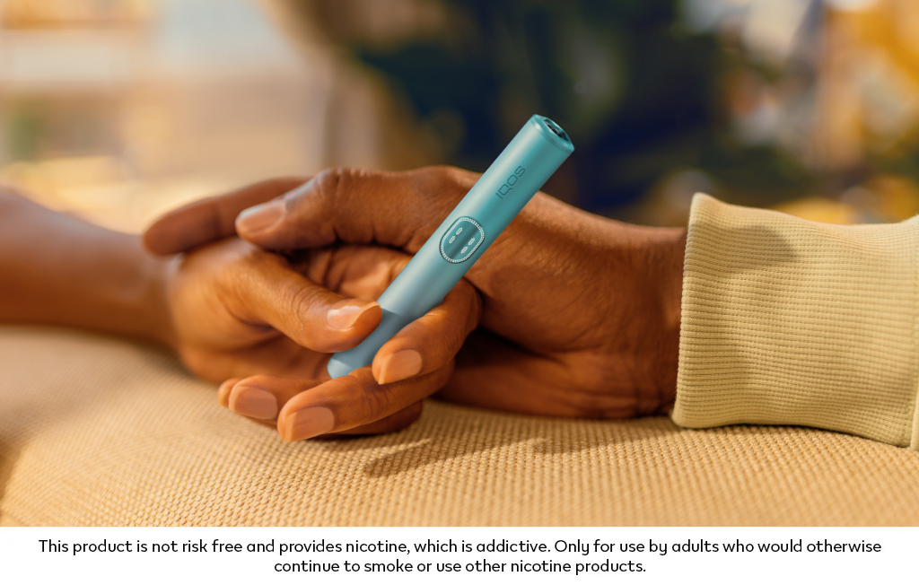 One hand on top of another, holding a Breeze Blue IQOS ILUMA i PRIME holder.