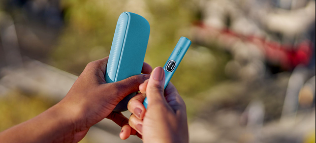 Woman's hands holding an IQOS ILUMA i Blue Breeze device
