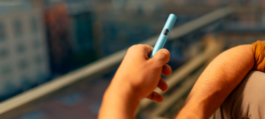 Male hand holding a Terracotta IQOS ILUMA i ONE device.