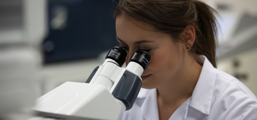 woman looking through microscope