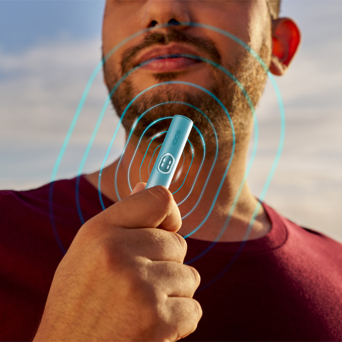 Man holding a blue IQOS ILUMA i PRIME device.