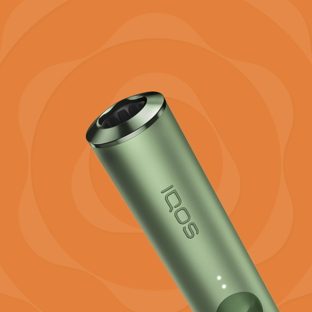 A Moss Green IQOS ILUMA holder in orange background.