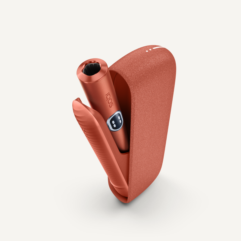 Συσκευή IQOS ILUMA i σε χρώμα Terracotta πάνω από τον φορτιστή της