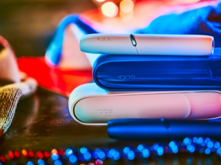 A white IQOS device and holder.
