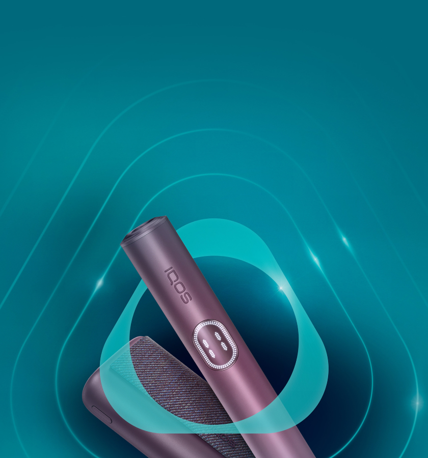 Συσκευή IQOS ILUMA i PRIME και ο φορτιστής της σε χρώμα Garnet Red σε τιρκουάζ φόντο