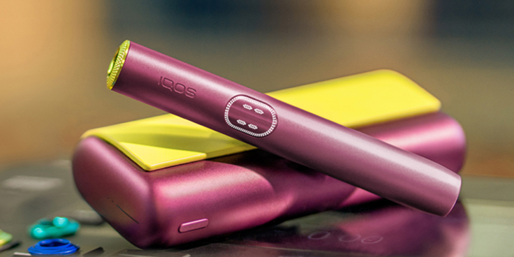 Συσκευή IQOS ILUMA i PRIME σε χρώμα Garnet Red με προσωποποιημένο περιτύλιγμα, πάνω από τον φορτιστή της