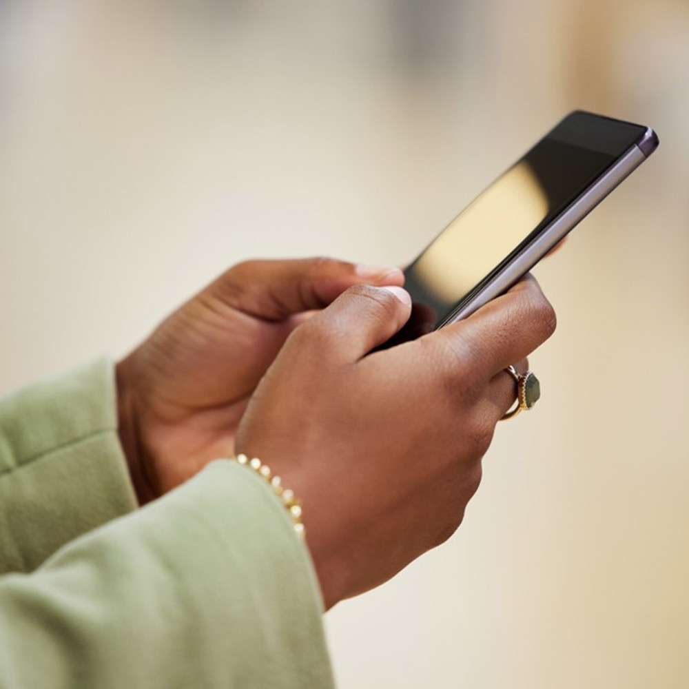 Hands holding smartphones and one IQOS device.