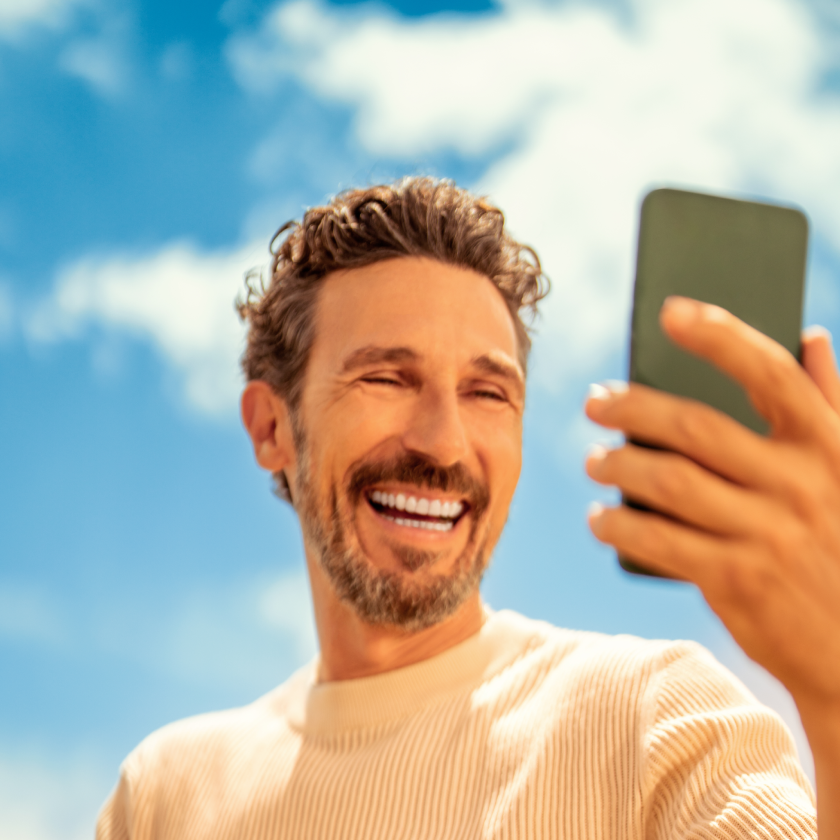 Man holds his mobile and smiles while looking at its screen