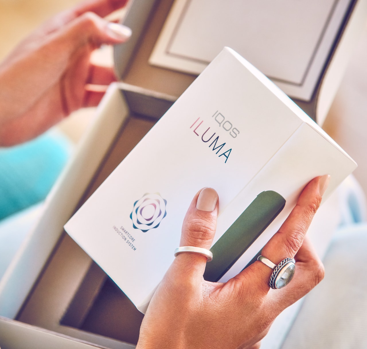 A person opening a box containing a new IQOS ILUMA.