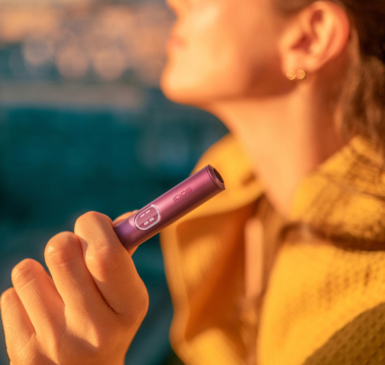 Woman holding a Garnet Red IQOS ILUMA device