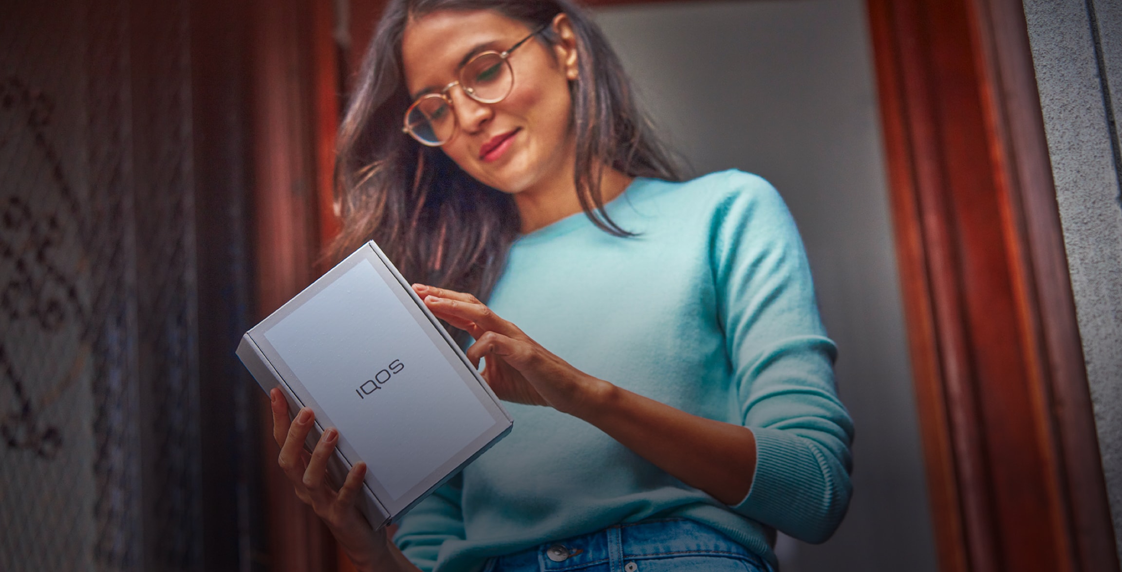 A smiling woman with an IQOS box.