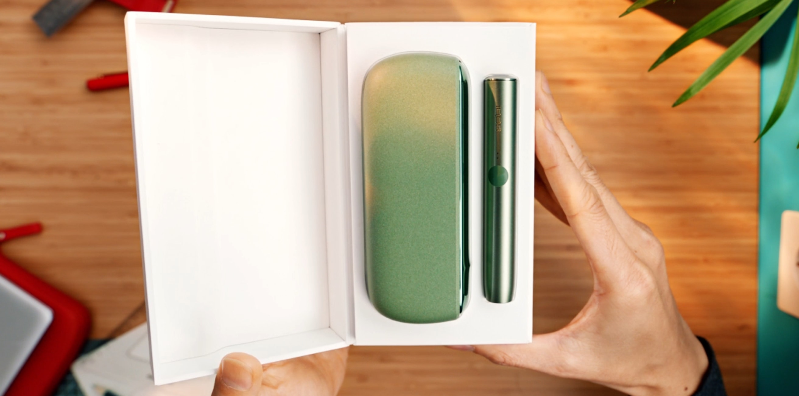 Βάση και φορτιστής τσέπης IQOS ILUMA σε χρώμα Moss Green μέσα σε ένα κουτί.