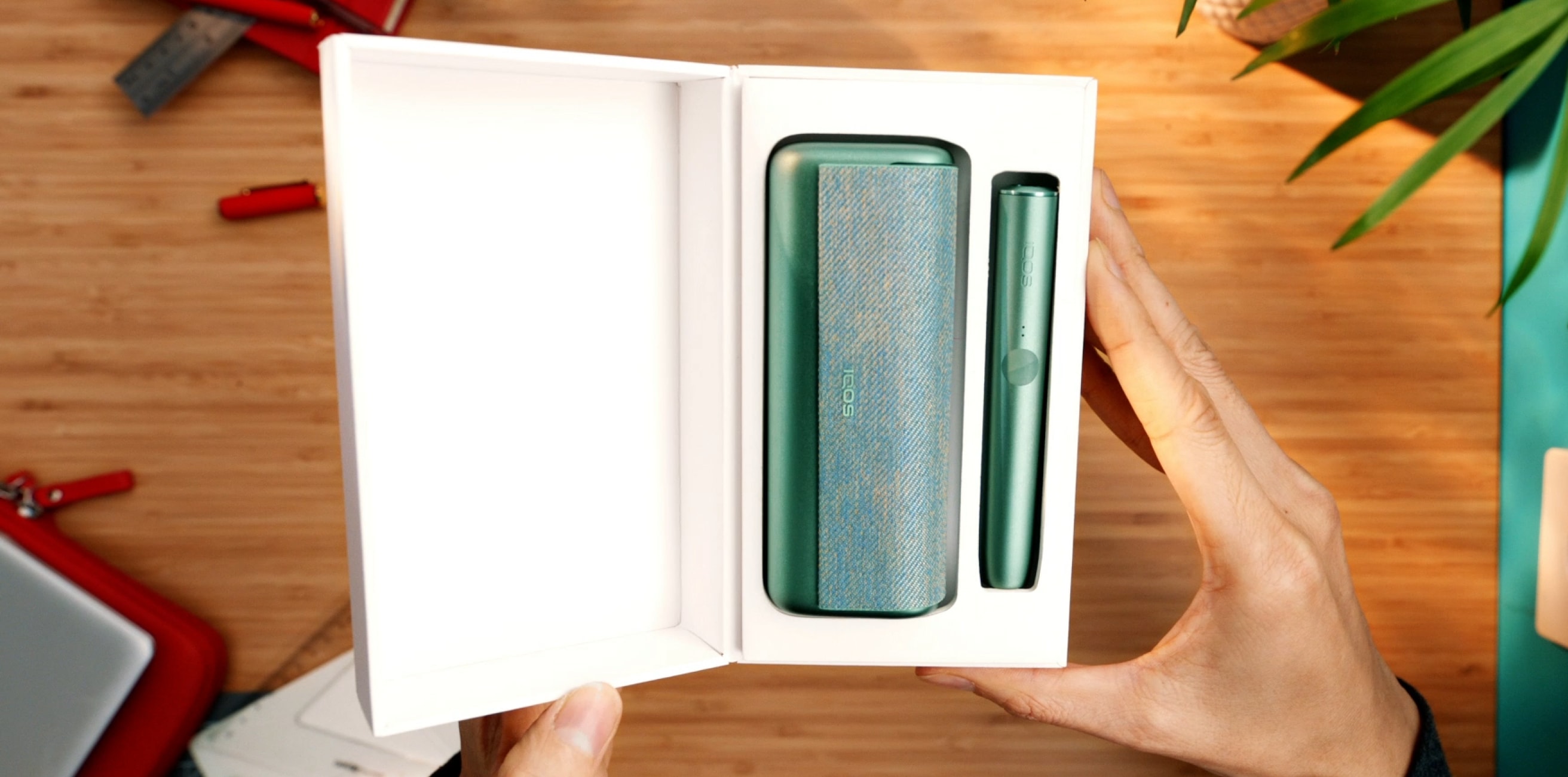 Βάση και φορτιστής τσέπης IQOS ILUMA PRIME σε χρώμα Jade Green μέσα σε ένα κουτί.