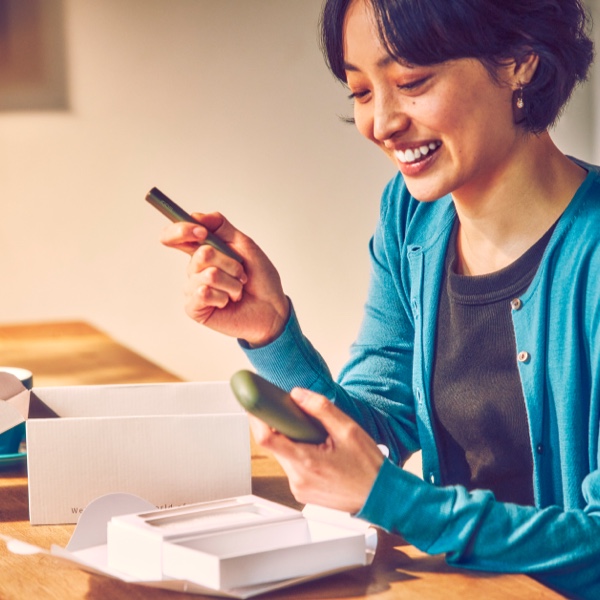 A smiling woman with an IQOS Pocket Charger and Holder.