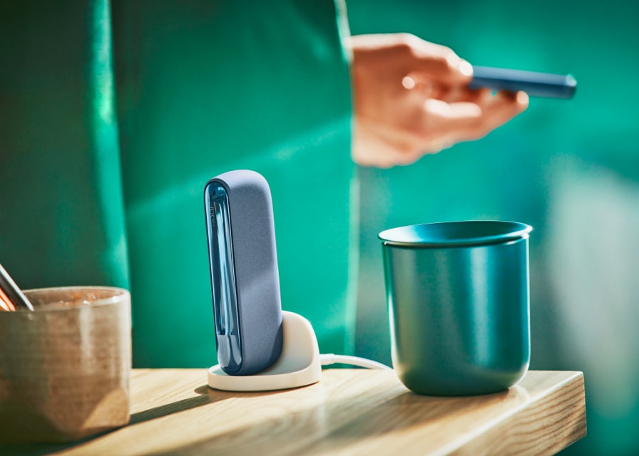 Man holds an IQOS ILUMA azure blue device.
