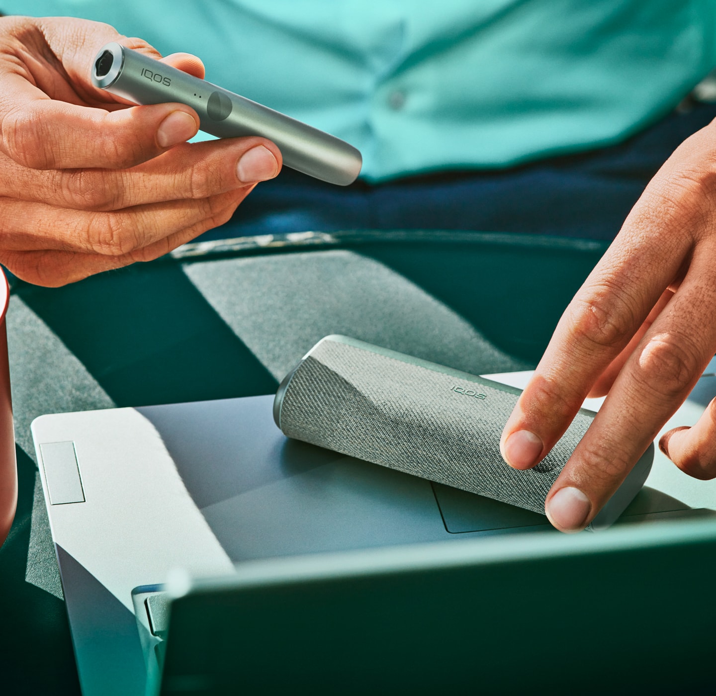 A man's hands opening an IQOS ILUMA device.