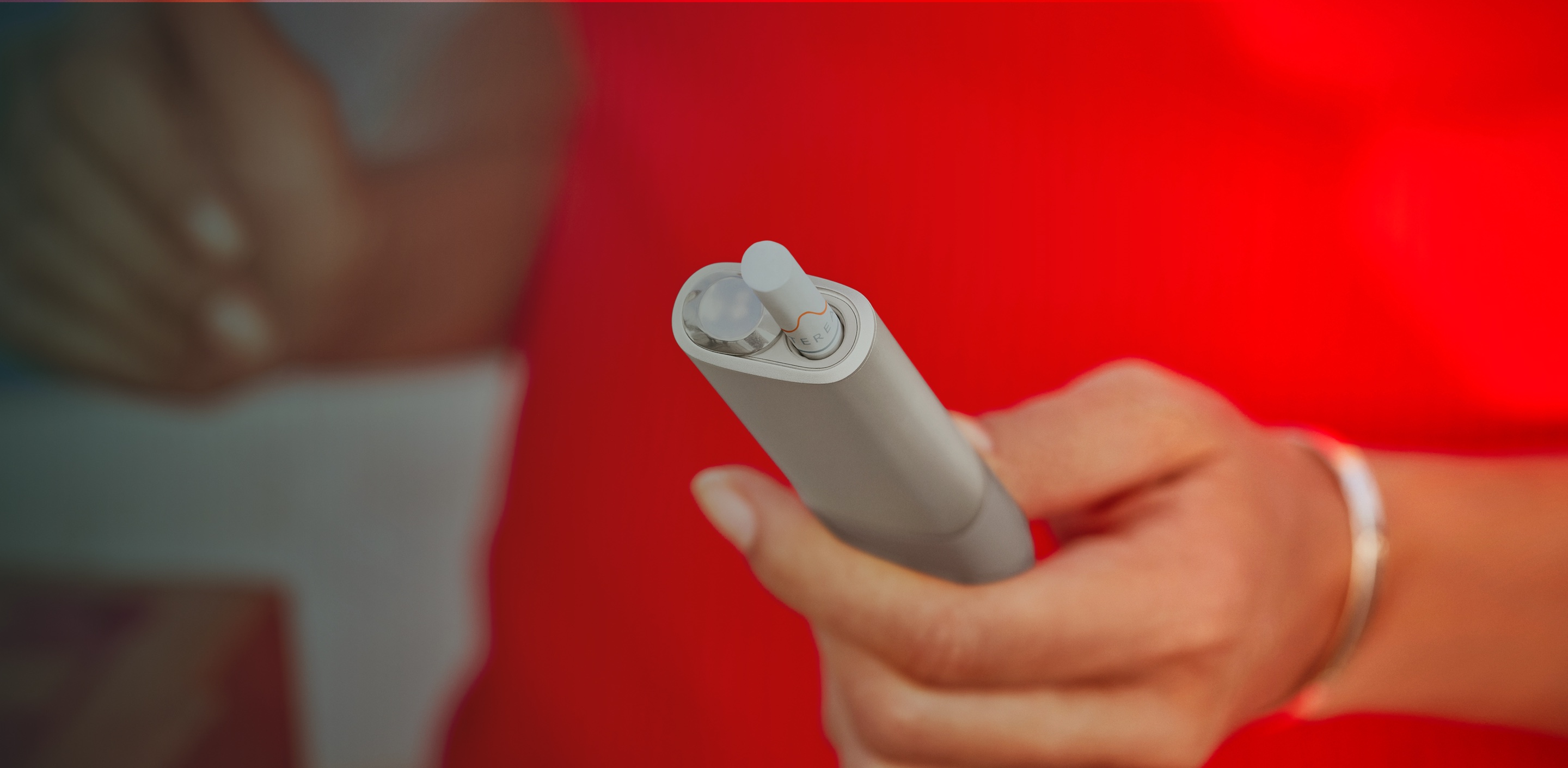 An IQOS ILUMA ONE device in a woman's hand.