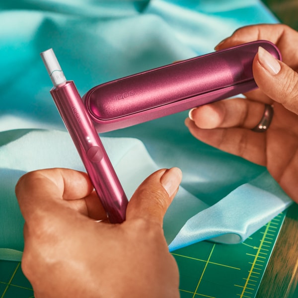 A bright IQOS ILUMA Pocket Charger and Holder in a person's hand.