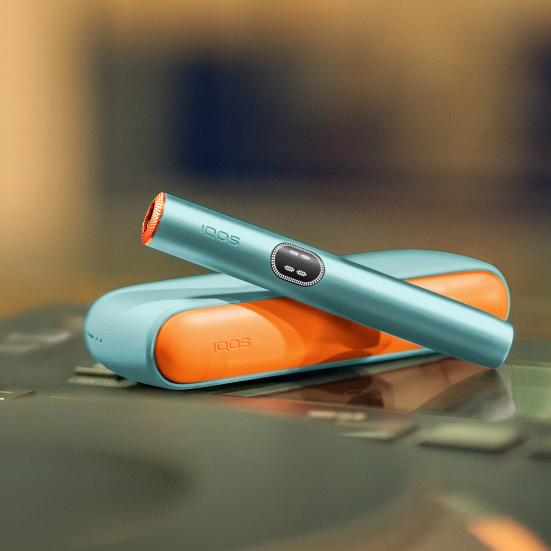 Breeze Blue IQOS ILUMA i device above its charger, with customed door and rings
