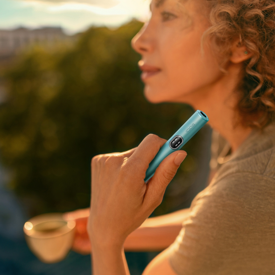Woman holding a blue IQOS ILUMA i device