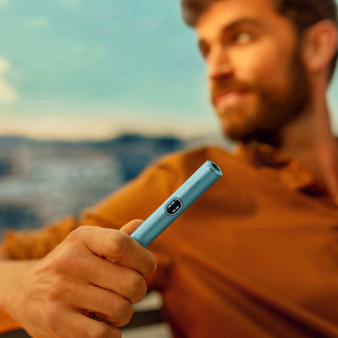 Man holding an IQOS ILUMA i device