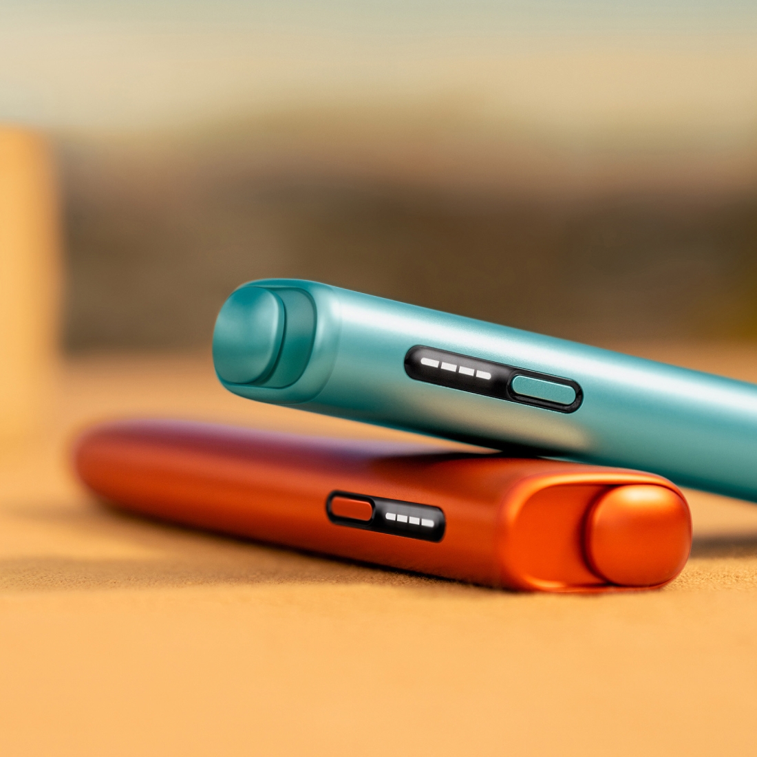 Blue IQOS ILUMA i ONE above a terracotta IQOS ILUMA i ONE