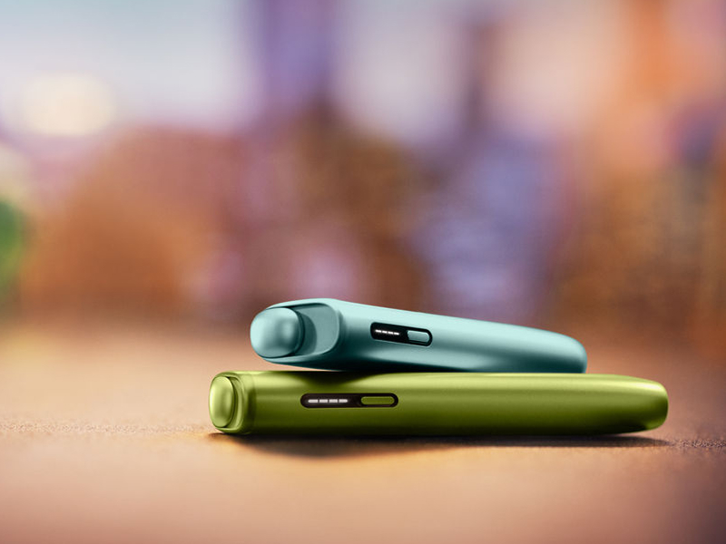 Blue IQOS ILUMA i ONE above a green IQOS ILUMA i ONE
