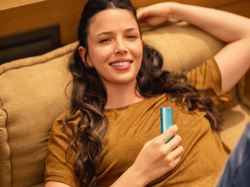 Purple IQOS ILUMA i ΟΝΕ device on a light turquoise background