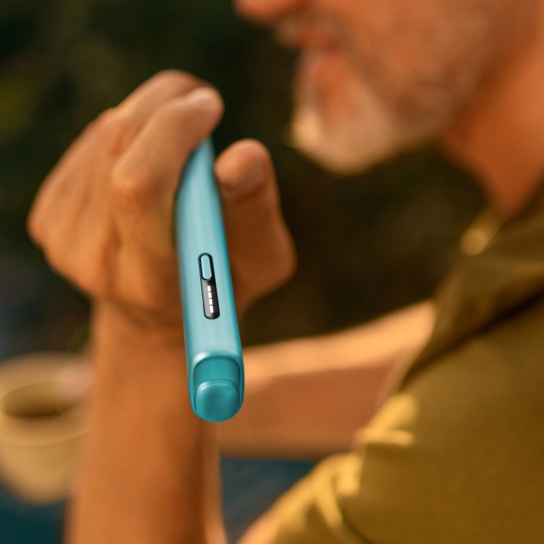 Detail of hand holding a blue IQOS ILUMA i ONE device