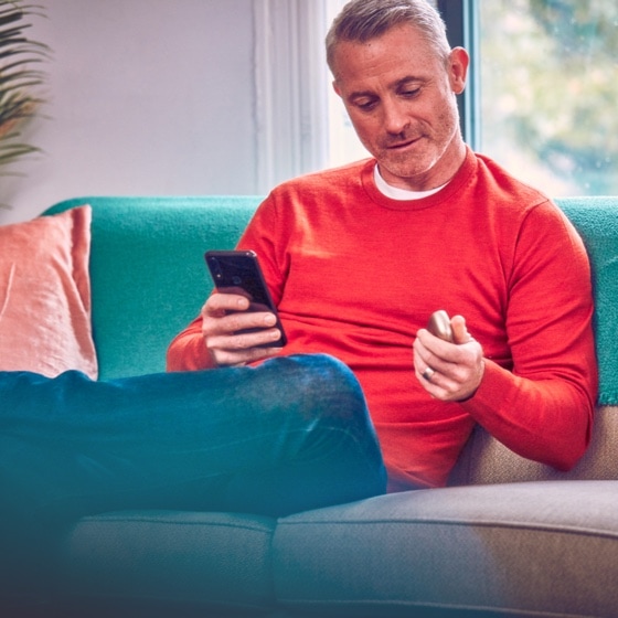 Man with phone in one hand, IQOS device in the other