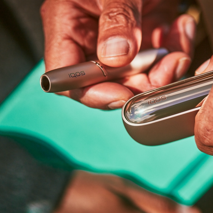 Χχρυσή βάση IQOS 3 DUO και φορτιστής στο χέρι