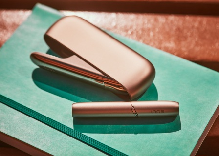 συσκευή IQOS 3 DUO χρυσή πάνω σε πράσινο τετράδιο