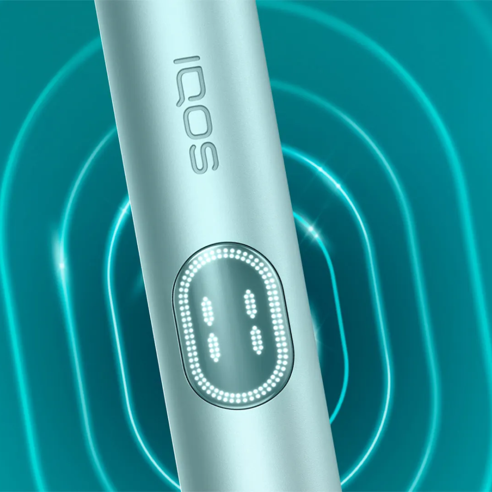 Συσκευή IQOS ILUMA i PRIME σε χρώμα Breeze Blue σε κοντινή απόσταση, σε γαλάζιο, κυματιστό φόντο.