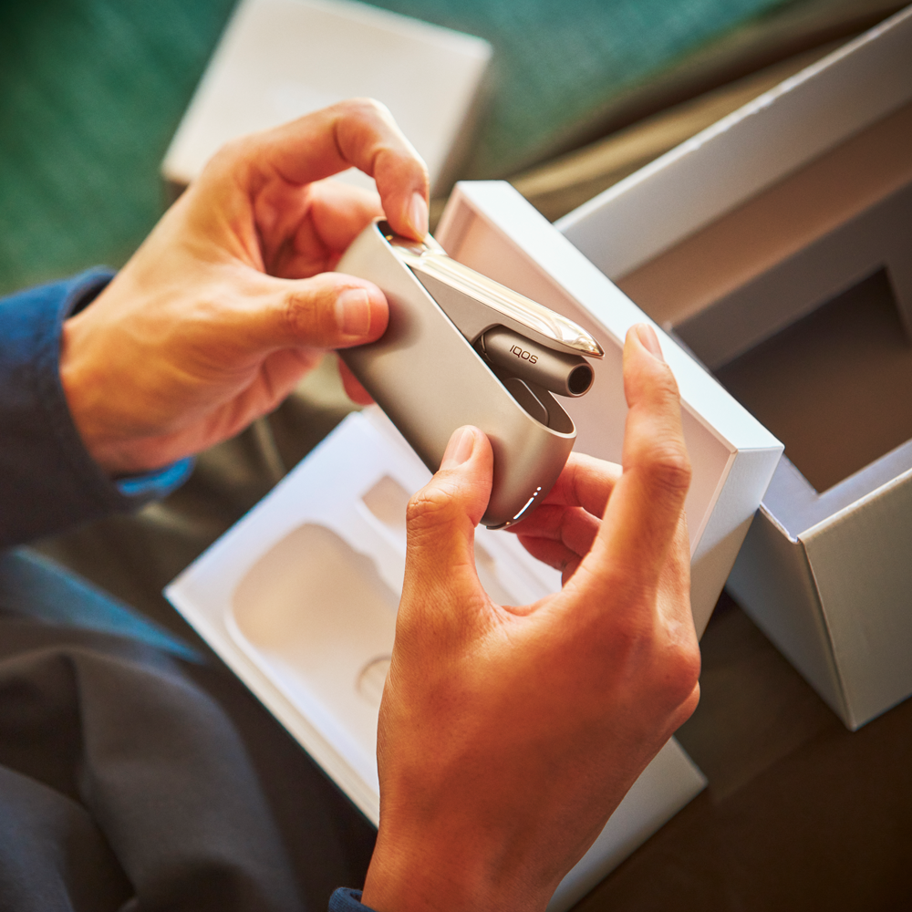 person opening an iqos package person opening an iqos package