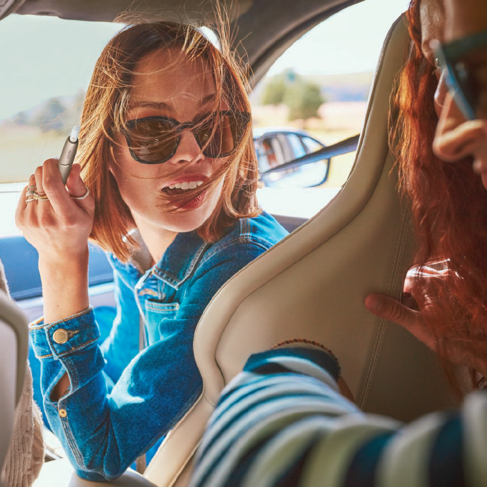 woman with sunglasses doing IQOS woman with sunglasses doing IQOS