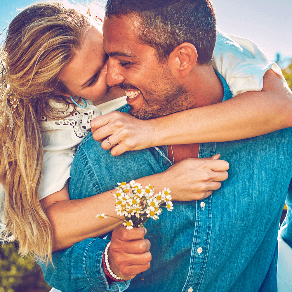 couple hugging and laughing. The man holds flowers couple hugging and laughing. The man holds flowers