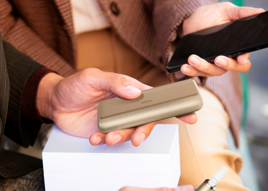 Man holds an IQOS ILUMA azure blue device.